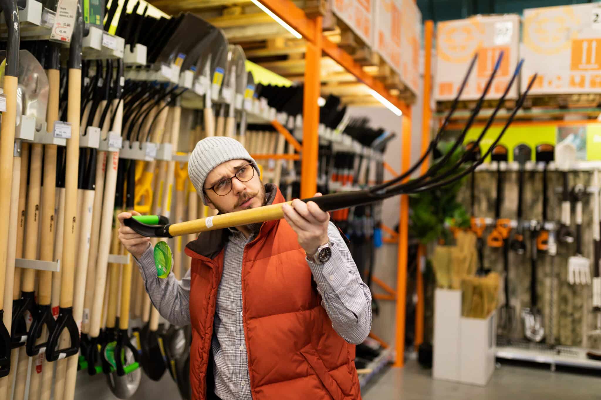 male customer in a hardware store chooses a garden pitchfork